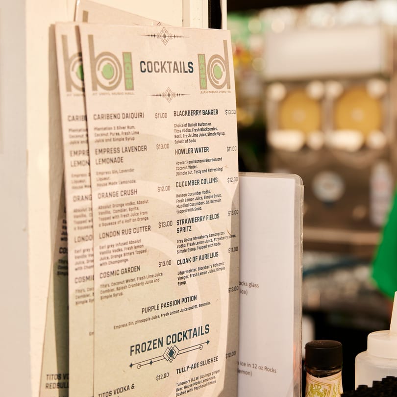 A close-up of the PROPER BURGER Downtown cocktail menu, featuring various drink options and prices.