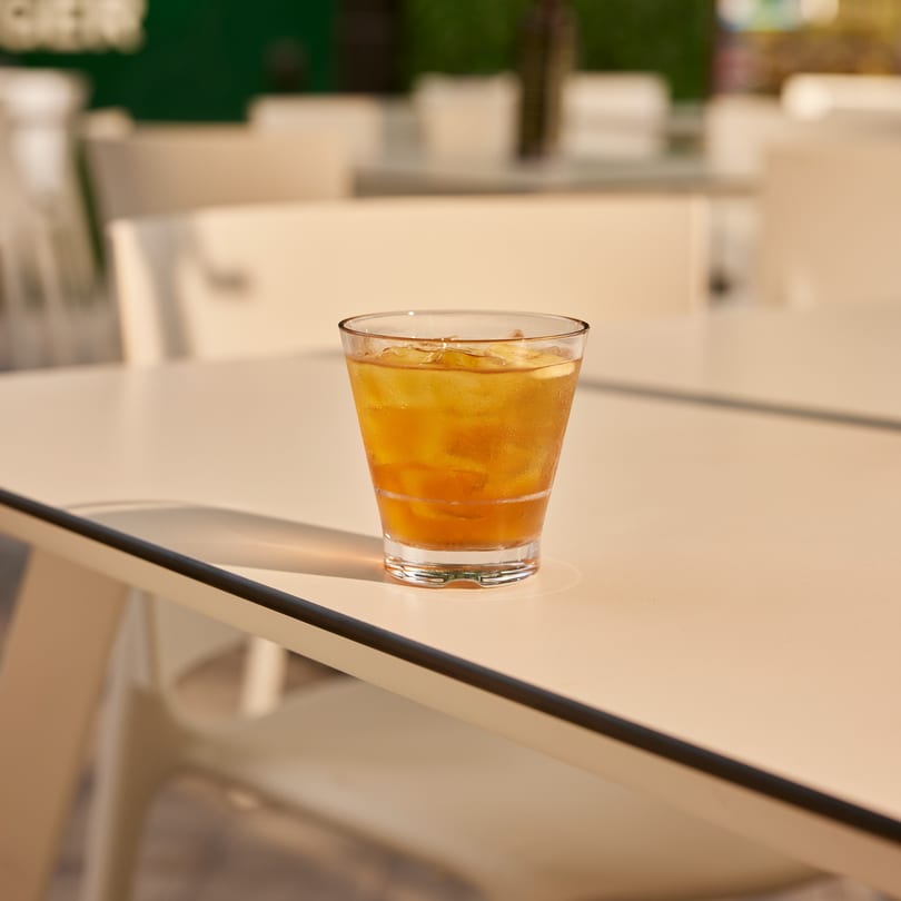 Iced tea in a glass on a white outdoor table at PROPER BURGER Downtown.