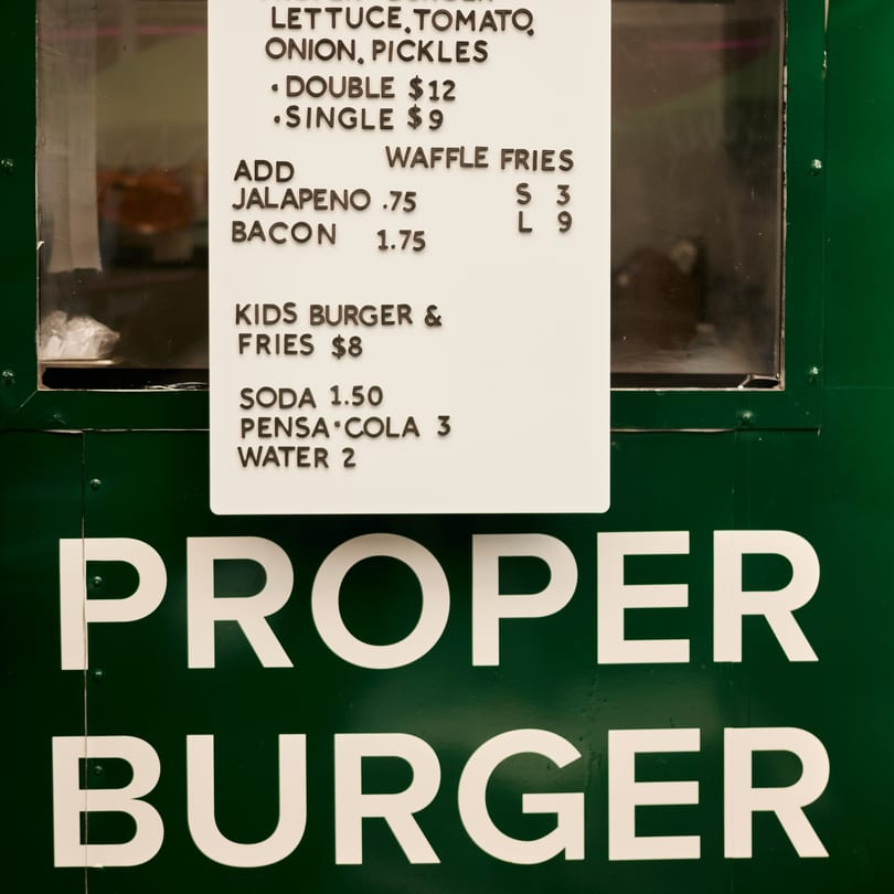 PROPER BURGER Downtown menu board with burger, waffle fries, and drink options.